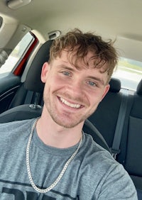 a young man smiling in the back seat of a car